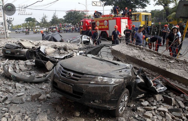 Firefighters stand near damaged vehicles after an earthquake struck Cebu city