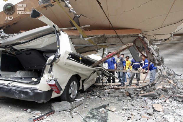 Residents inspect a car after a concrete block fell on it during an earthquake in Cebu city