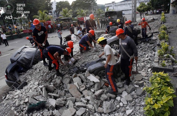 Rescuers clear debris from buried vehicles after an earthquake struck Cebu city