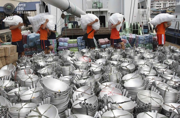 Members of Philippine Coastguard carry sacks filled with relief goods to load on-board the BRP Corregidor, flagship of the Philippine coast guard, at a port in Manila