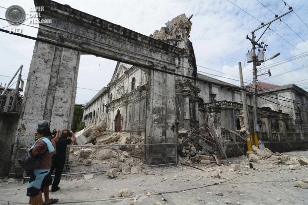 Local photographers takes pictures of the damage to the historic Basilica Minore of Santo Nino de Cebu after an earthquake hit the church in Cebu City
