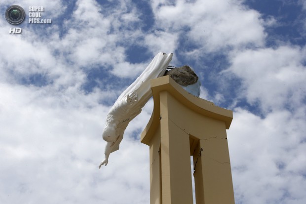 A statue of Jesus hangs beside the collapsed Our Lady of Light church in Loon