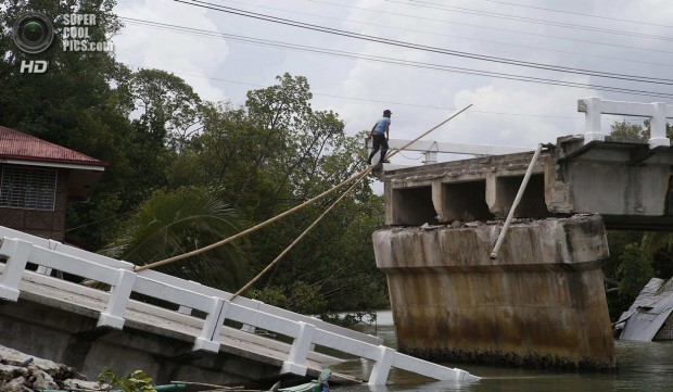 A policeman stands at the edge of a damaged bridge in Loon, Bohol, a day after an earthquake hit central Philippines