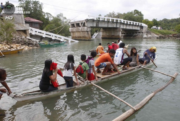 Villagers ride on a boat to cross a river after a bridge was damaged in Loo