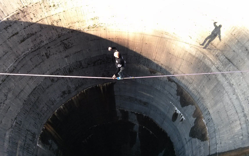 Смельчак слэклайнер пересекает 61-метровый слив водохранилища