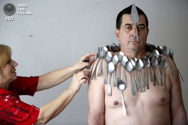 Muhibija Buljubasic, 56, stands as his wife Senija puts cutlery on his body in Srebrenik