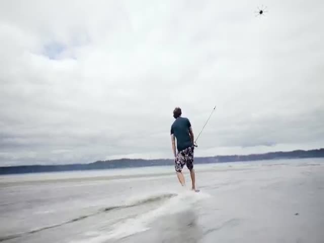 Серфер катается на волнах с помощью дрона